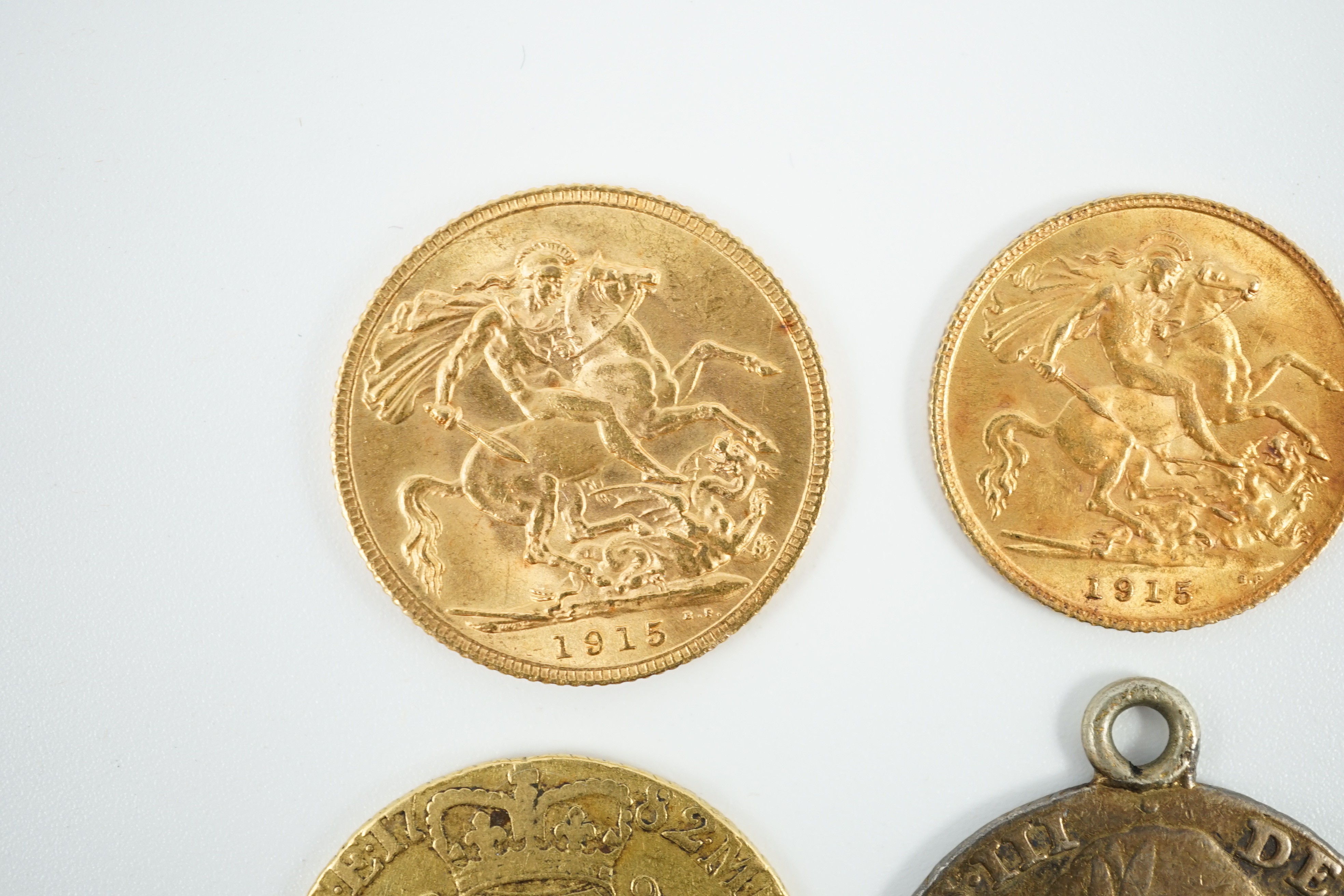 A George V 1915 gold sovereign and a 1915 gold half sovereign, a George III 1782 gold guinea(worn) and a George III 1787 shilling, with pendant mount.